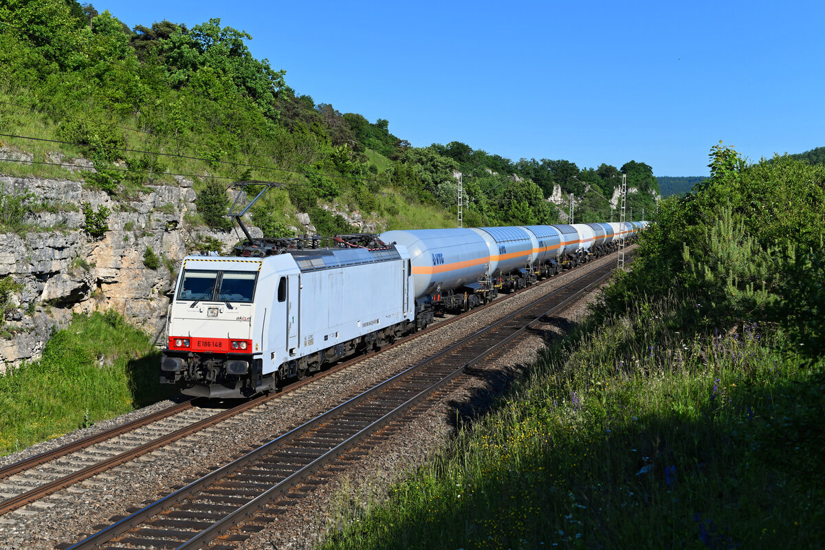 Die an die HSL vermietete 186 148 von akiem beförderte am 13. Juni 2021 einen Ganzzug bestehend aus Gaskesselwagen westwärts. Die aus Österreich kommende Leistung wurde aufgrund von Bauarbeiten zwischen Regensburg und Nürnberg über das Almühltal umgeleitet. Die Aufnahme entstand bei Hagenacker.