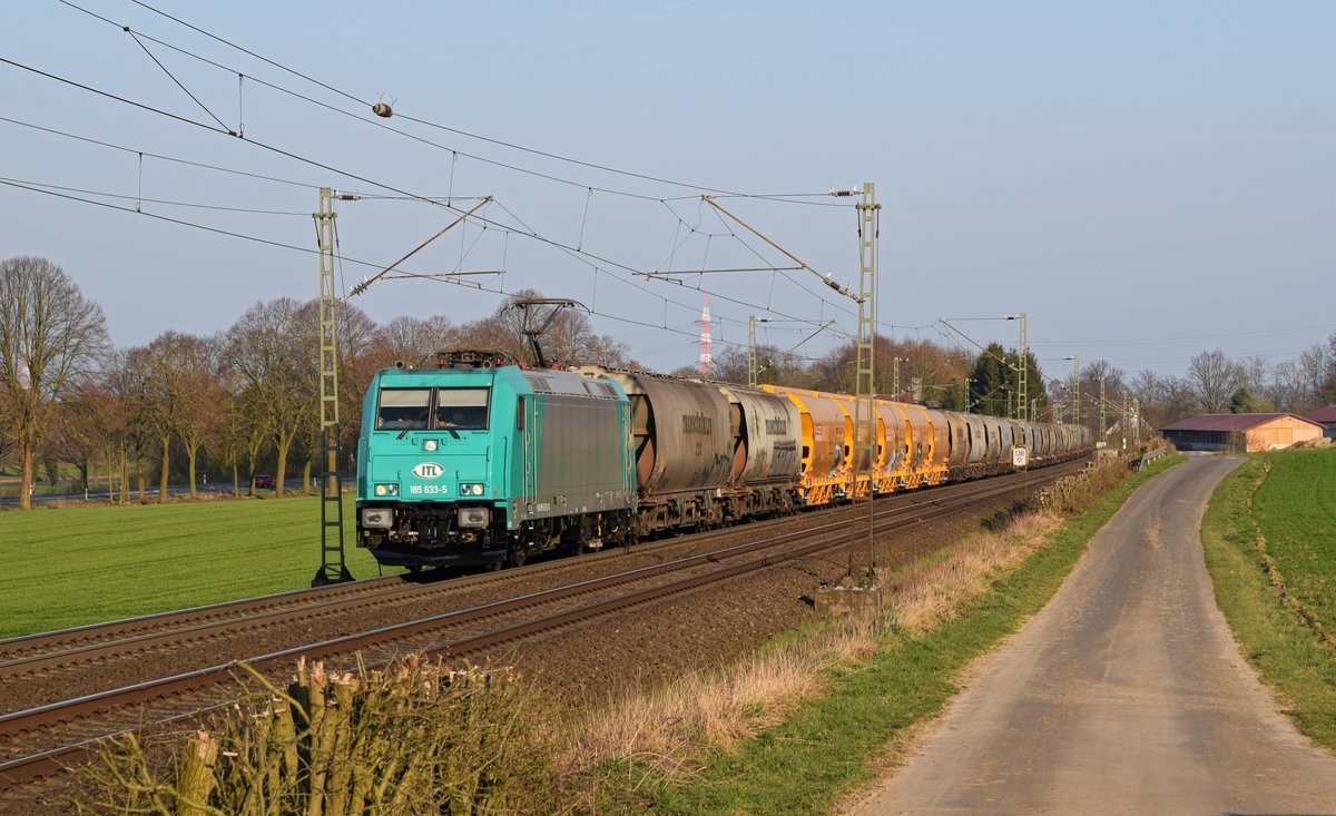 Die an ITL vermietete Alpha Trains 185 633 schleppt einen Getreidezug am 28.03.17 zwischen Bohmte und Ostercappeln in Richtung Osnabrck.