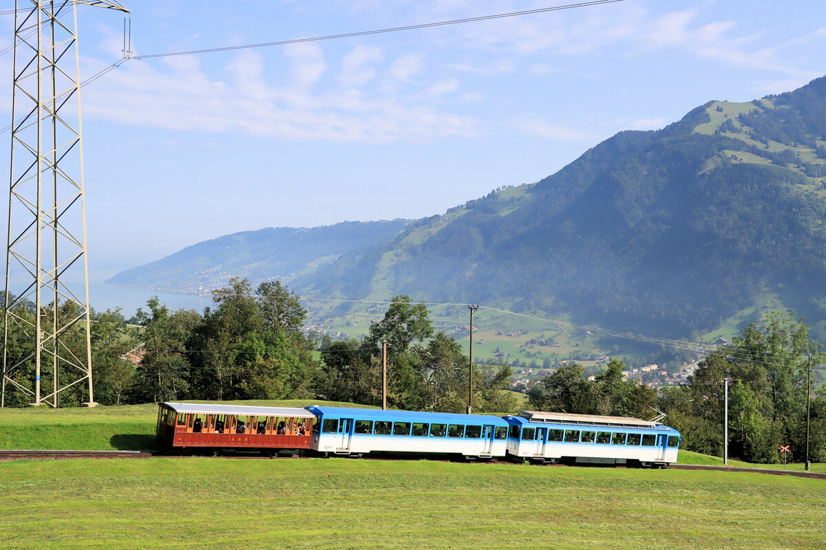 Die Arth Rigi Bahn mit Blick auf den Zugersee. Dem Pendelzug mit Triebwagen 15 und Steuerwagen 25 (1982) ist der alte Zweiachser-Personenwagen 33 (1875) vorgestellt. 21.August 2021 