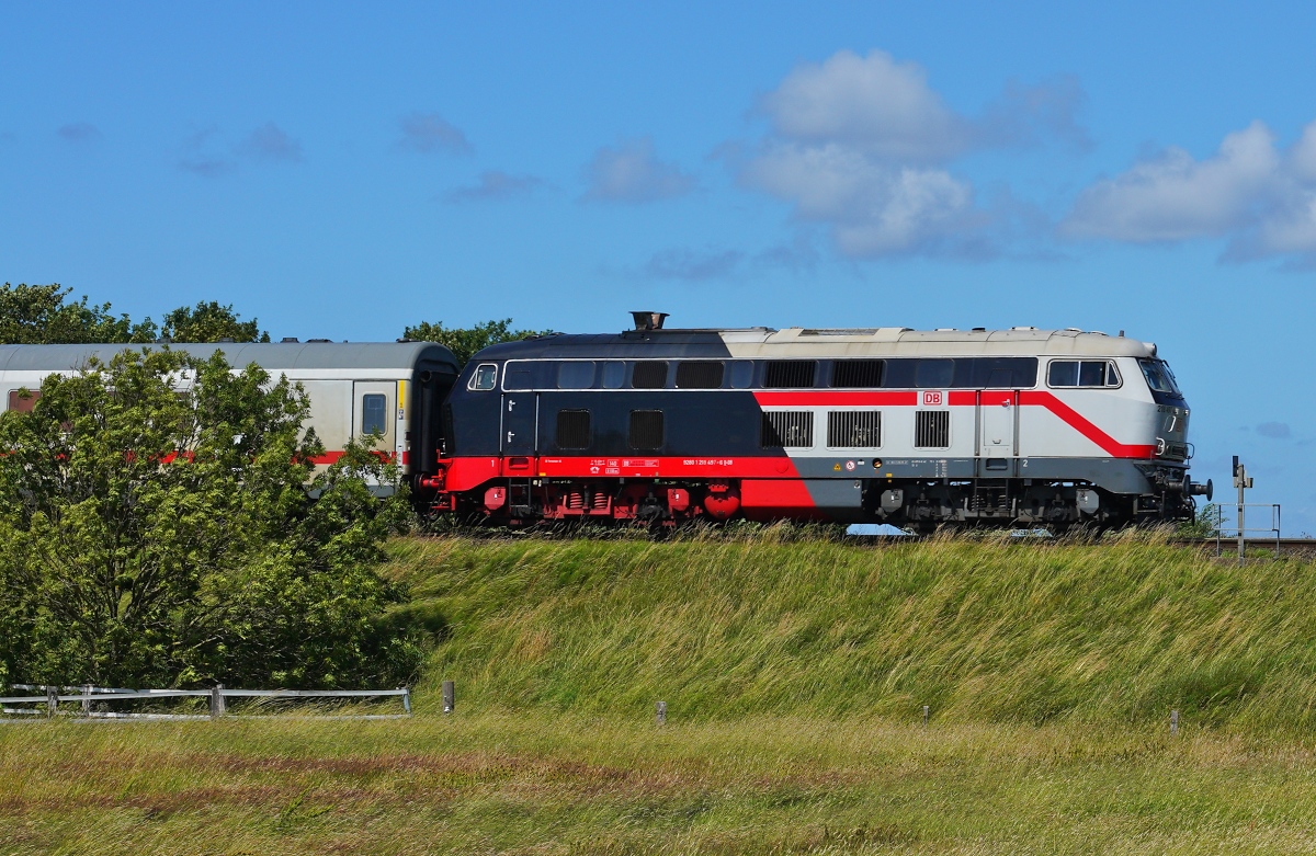 Die auffälligste Gestaltung der auf der Marschbahn anzutreffenden 218 weist sicherlich die 218 497-6 auf, hier eine Seitenansicht, als sie vor einem IC am 28.06.2024 bei Morsum in Richtung Festland fährt
