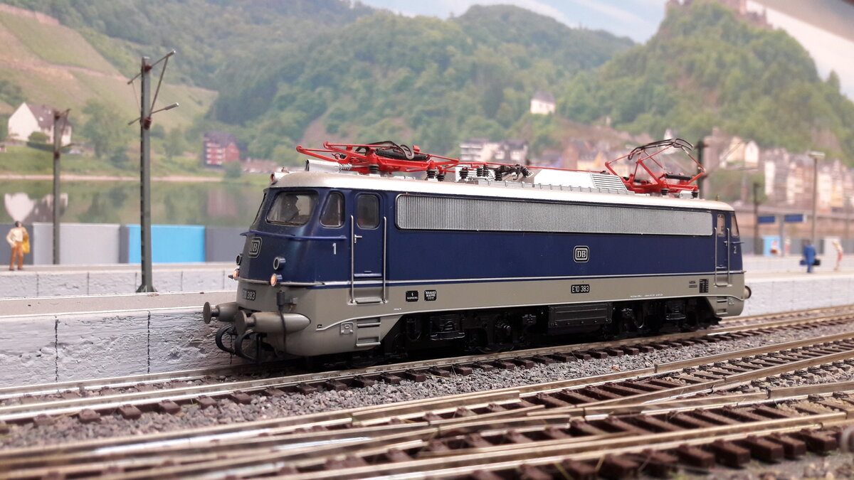 Die Baureihe E10,  5 Vorserienmaschinen ( dazu gab es schon Bilder und Erklärungen) . Die ersten Serienlokomotiven waren die E10 Kasten ab 1956.  Die Baureihenbezeichnungen durchliefen die Ordnungsnummern (ab 1968 )   110 / 112 / 113 / 114 / 115 .  Da die Lok als Einheitslokomotive entwickelt wurde, gab es in der Kastenvariante  noch die E40 (140) , E41 (141) und die E50 (150 ).  Die ersten Kasten E10  waren die E10.1 , spätere Ausführungen der Kasten E10  bekamen die Doppellampen vorne , das waren die E10.2 .  Ab Maschine 288 wurde dann die Bügelfaltenform eingeführt, welche zuvor schon an den Rheingoldmaschinen realisiert wurde. Diese wurden als E10.3 bezeichnet , die Rheingoldmaschinen liefen unter E10.12. Es gab unglaublich viele Varianten , mit Regenrinne und ohne, verschiedenste Lamellenausführungen, usw. usw .  Auch etliche Farbvarianten hat die Lok durchgemacht
Hier das Modell der Ursprungsvariante Bügelfalten E10 , silberne Regenrinne, durchgehendes Doppeldüsenlüftergitter, verkleidete Pufferbohlen, Griffumlauf vorne. Jedoch dieses mal in der einer Farbversuchsvariante. Es sollte eine bessere Sichtbarkeit der Lokomotiven erreichen. Es wurden 3 verschiedene Grautöne probiert, wobei wir hier den mittleren Ton sehen.   Modell E10 383  Roco 43793 DC digital