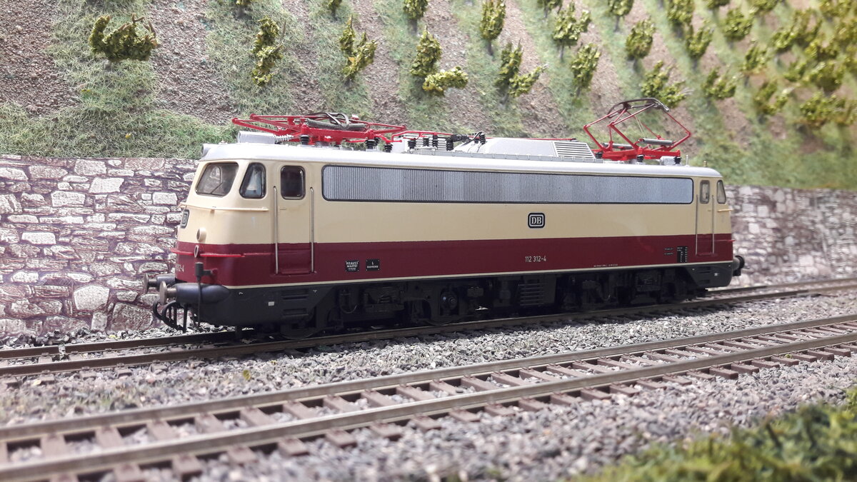 Die Baureihe E10, 5 Vorserienmaschinen ( dazu gab es schon Bilder und Erklärungen) . Die ersten Serienlokomotiven waren die E10 Kasten ab 1956. Die Baureihenbezeichnungen durchliefen die Ordnungsnummern (ab 1968 ) 110 / 112 / 113 / 114 / 115 . Da die Lok als Einheitslokomotive entwickelt wurde, gab es in der Kastenvariante noch die E40 (140) , E41 (141) und die E50 (150 ). Die ersten Kasten E10 waren die E10.1 , spätere Ausführungen der Kasten E10 bekamen die Doppellampen vorne , das waren die E10.2 . Ab Maschine 288 wurde dann die Bügelfaltenform eingeführt, welche zuvor schon an den Rheingoldmaschinen realisiert wurde. Diese wurden als E10.3 bezeichnet , die Rheingoldmaschinen liefen unter E10.12. Es gab unglaublich viele Varianten , mit Regenrinne und ohne, verschiedenste Lamellenausführungen, usw. usw . Auch etliche Farbvarianten hat die Lok durchgemacht Hier das Modell der Bügelfalten E10/112 ... 112 312-4 in TEE Farben, Regenrinne, durchgehendes Doppeldüsenlüfterband, verkleideten Pufferbohlen , diesmal mit Rehling vorne  . Modell Roco 43792 DC digital