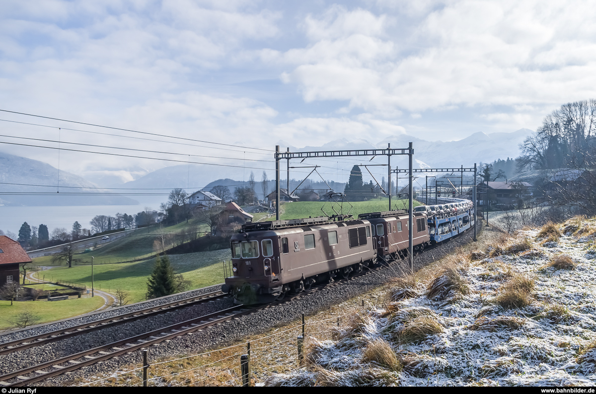 Die beiden BLS Re 4/4 181 und 177 ziehen am 18. Januar 2015 einen mit italienischen Neuwagen beladenen Autozug bei der ehemaligen Haltestelle Kumm dem Thunersee entlang Richtung Norden.