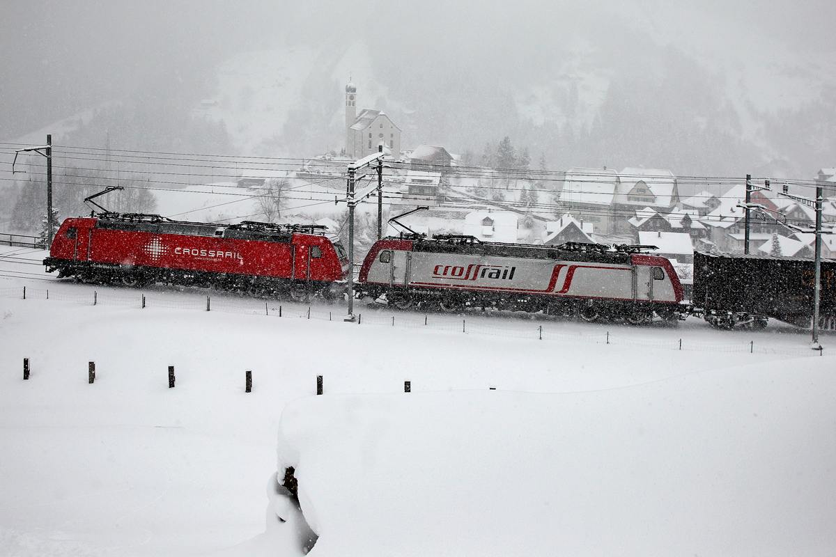 Die beiden Crossrail Loks 185 595-6 und 185 602 kämpfen sich durch dichten Schneefall mit einem Containerzug den Berg hoch,hier zu sehen vor der Kulisse von Wassen.Bild vom 30.12.2014