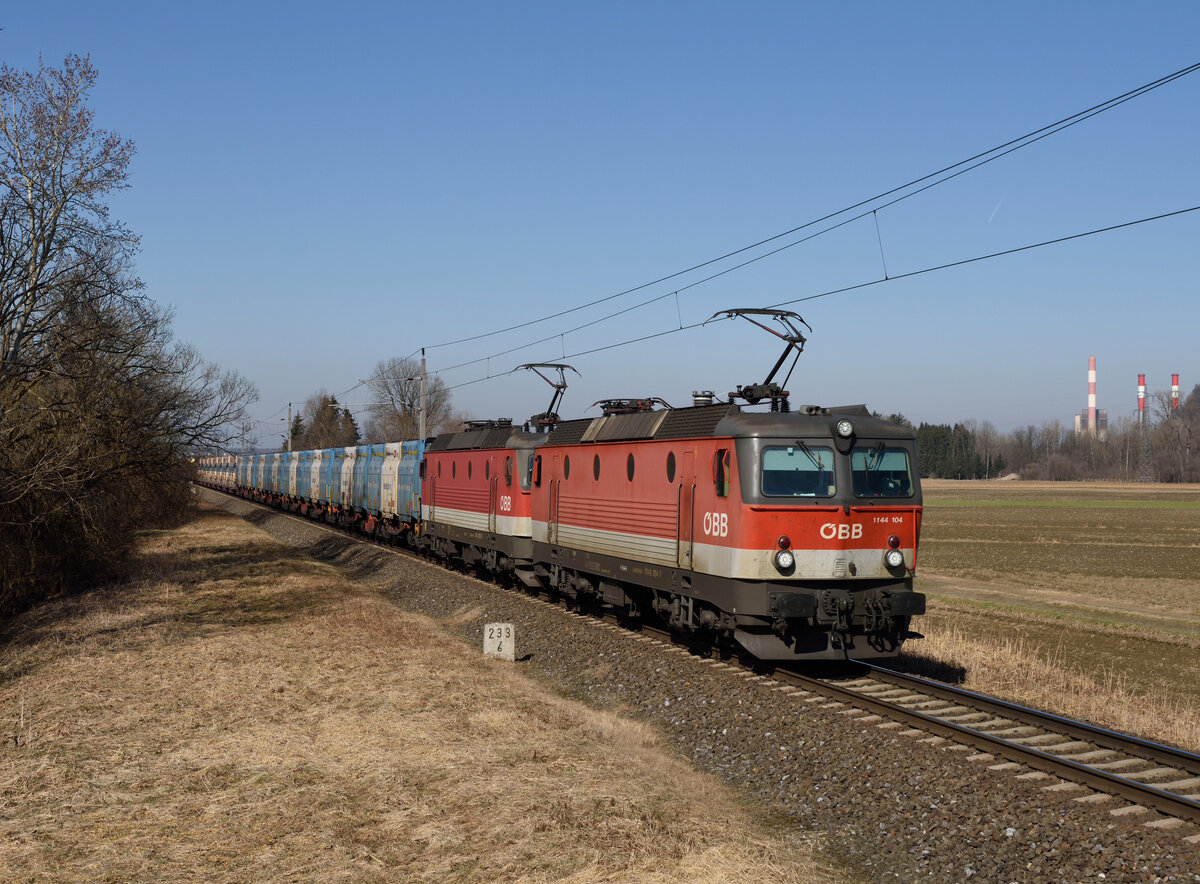 Die beiden Loks 1144 103 und 1144 223 traktionierten am 02. März 2021 den Leererzug 47407 auf der Relation von Leoben Donawitz nach Spielfeld-Straß. Das Bild entstand in Wildon, im Hintergrund zu sehen sind die aktuell höchsten Bauwerke der Steiermark nämlich die jeweils 175 Meter hohen Schornsteine des Fernheizkraftwerkes bzw. jene des Gas- und Dampfkraftwerks Mellach