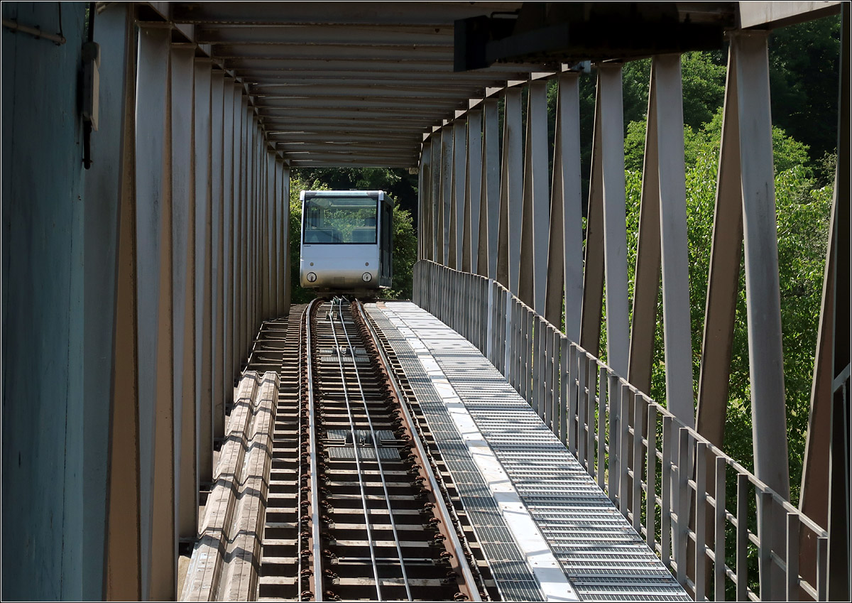 Die Bergbahn Künzelsau - 

Von der Talstation aus kann durch eine Glaswand auf die Strecke innerhalb der Fachwerkbrücke geblickt werden. An den ausgeschalteten Scheinwerfern ist die Bergfahrt der Bahn zu erkennen.

29.07.2021 (M)