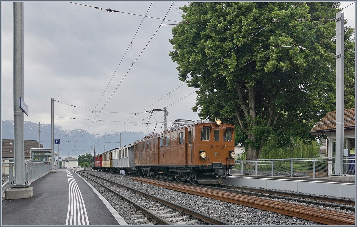 Die Blonay Chamby  Bernina Bahn Ge 4/4 81 bei der Rückfahrt nach Blonay mit ihrem  Riviera Belle Epoque  fährt in St-Légier Gare durch. Trotz grundlegendem Umbau der Station St-Légier Gare steht das Ensemble des schönen grossen Baums sowie des kleinen Stationsgebäude weiterhin an ihren Platz. 

9. Juni 2019