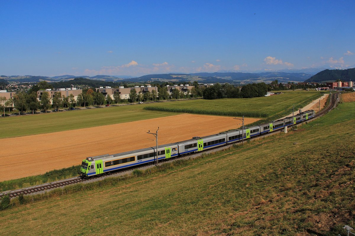 Die BLS in der grossen Hitze: Erst ein paar kleine Wölkchen über den Alpen, sonst brennt die Gluthitze, während ein NPZ von Thun her nach Bern und weiter nach Langnau im Emmental fährt. Der Zug hat gerade  zwei  Jumbo -Wagen, das sind aus einstigen Einheitswagen hergestellte Doppelwagen mit Tiefeinstieg. Im Hintergrund sieht man auch die entstehende Doppelspur. 26.Juli 2018 