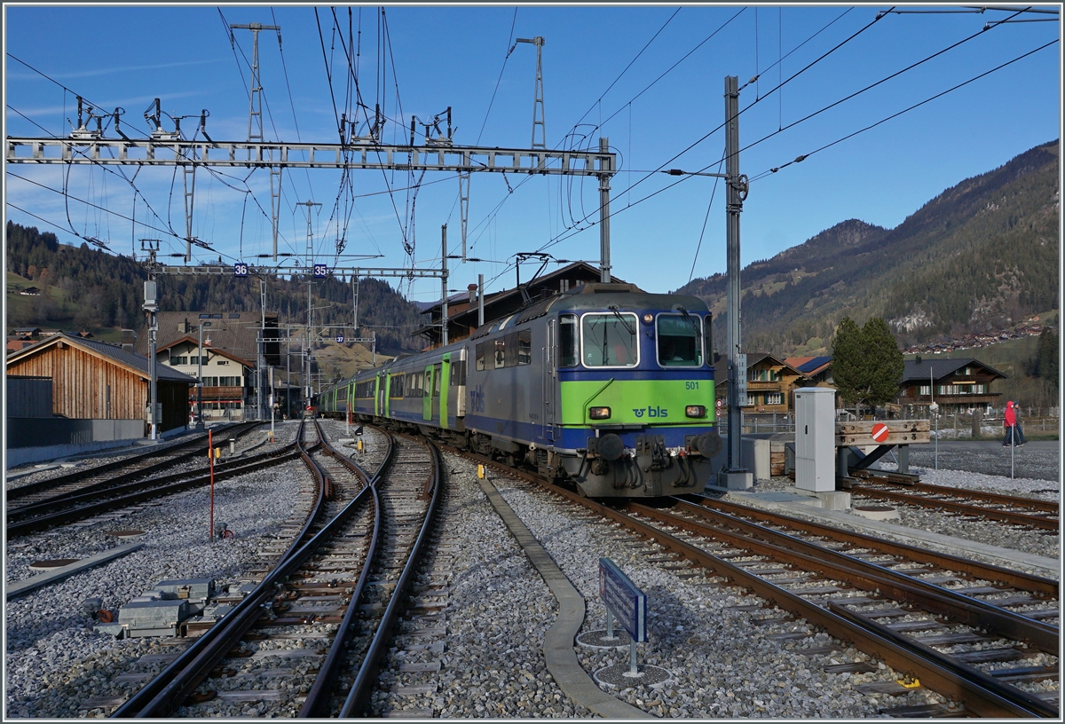 Die BLS Re 4/4 II 501 erreicht mit ihrem RE 4073 von Interlaken Ost ihr Ziel Zweisimmen. 
Neben dem schöne Zug ist auch ein Blick auf die Gleis- und Fahrleitungsanlage im Linken Bildteil interessant: Auf dem nach links führenden Gleis wird ab Dezember 2022 die Schmalspurlok den Umspurzug Montreux - Interlaken - Montreux verlassen bzw. zu diesem gelangen. Dieses Manöver benötigt auch eine Umstellung der Fahrleitungsspannung, was an den recht zahlreichen Umschaltern auf dem Fahrleitungsmast zeigt. 

25. November 2020