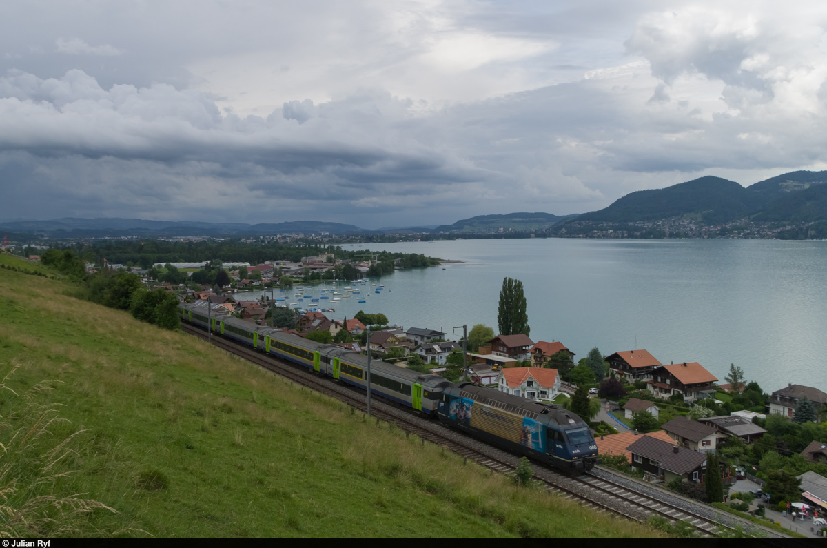 Die BLS Re 465 008  Niederhorn  mit schon etwas abgeschossener Werbung für die GoldenPass-Linie (was zum Image der Linie bei der BLS passt) fährt am 14. Juni 2015 mit einem Entlastungszug Thun-Frutigen-Thun bei Einigen am Thunersee in Richtung Spiez.