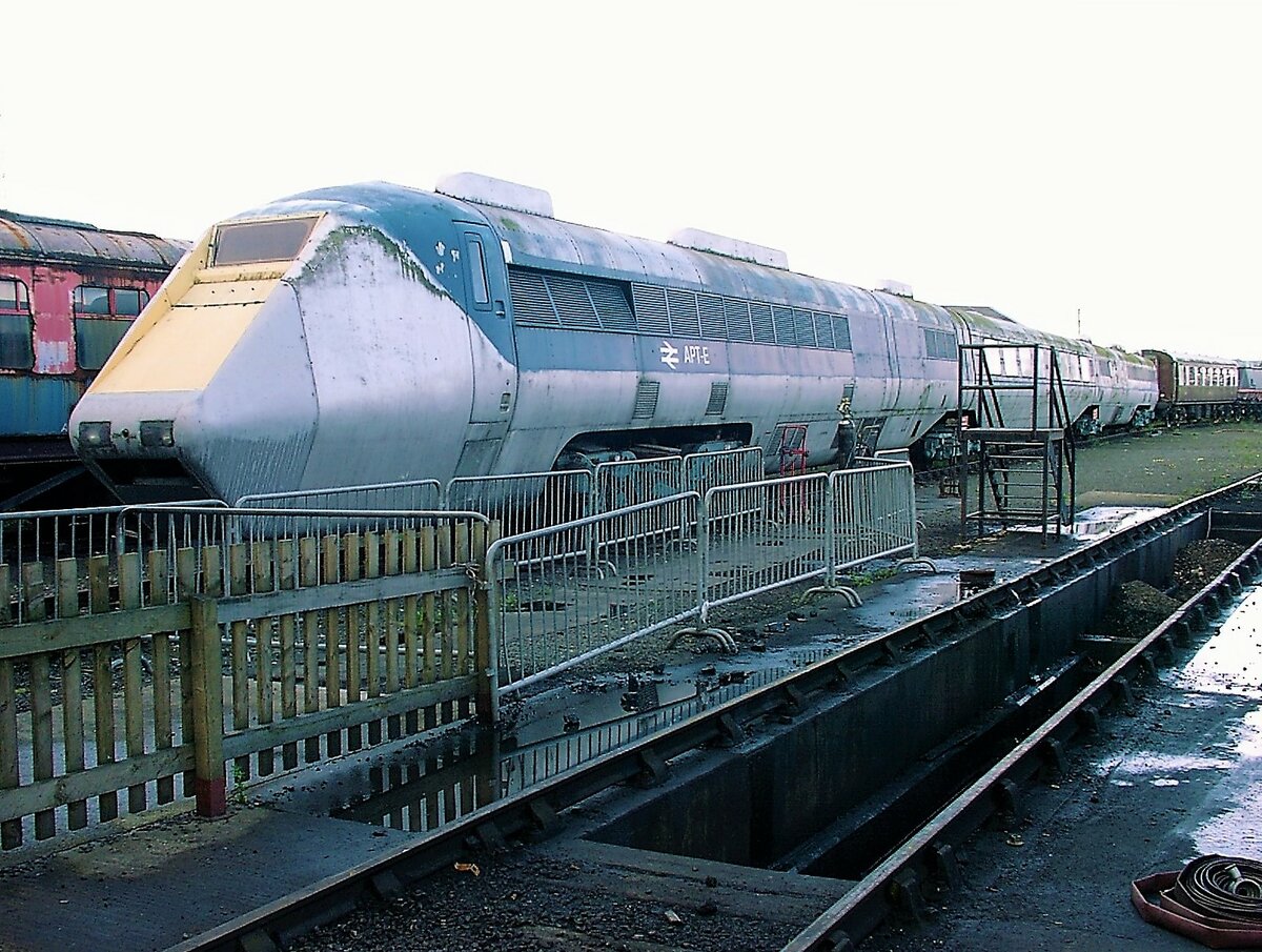 Die britischen Advanced Passenger Trains waren Personenzüge mit Neigetechnik der British Rail (BR), die mit dem Ziel hoher Reisegeschwindigkeiten entwickelt wurden. Dabei sind zwei Unterarten zu unterscheiden: Zum einen existiert der APT-E (E für Experimental), der mit einer Gasturbine betrieben wurde und zum anderen der APT-P (P für Prototype), welcher elektrisch angetrieben wurde. Der hier am 27.8.2000 in York ausgestellte APT-E wurde 1975 der Öffentlichkeit vorgestellt. Auf Versuchsfahrten erreichte das Fahrzeug eine Höchstgeschwindigkeit von 242 km/h und legte die 159 Kilometer lange, ursprünglich für geringere Geschwindigkeiten ausgelegte Strecke zwischen London und Leicester in unter einer Stunde zurück. Schon 1976 zogen die BR diesen Testzug von den Strecken ab; er war für eine Verwendung im echten Personenzugdienst ohnehin nicht vorgesehen, da die Passagierkapazität mit zwei Mittelwagen in einem ungünstigem Verhältnis zu der aufwendigen Antriebstechnik mit je vier Gasturbinen stand. Heute ist der äußerlich aufgearbeitete Zug im Eisenbahnmuseum von Shildon zu besichtigen.