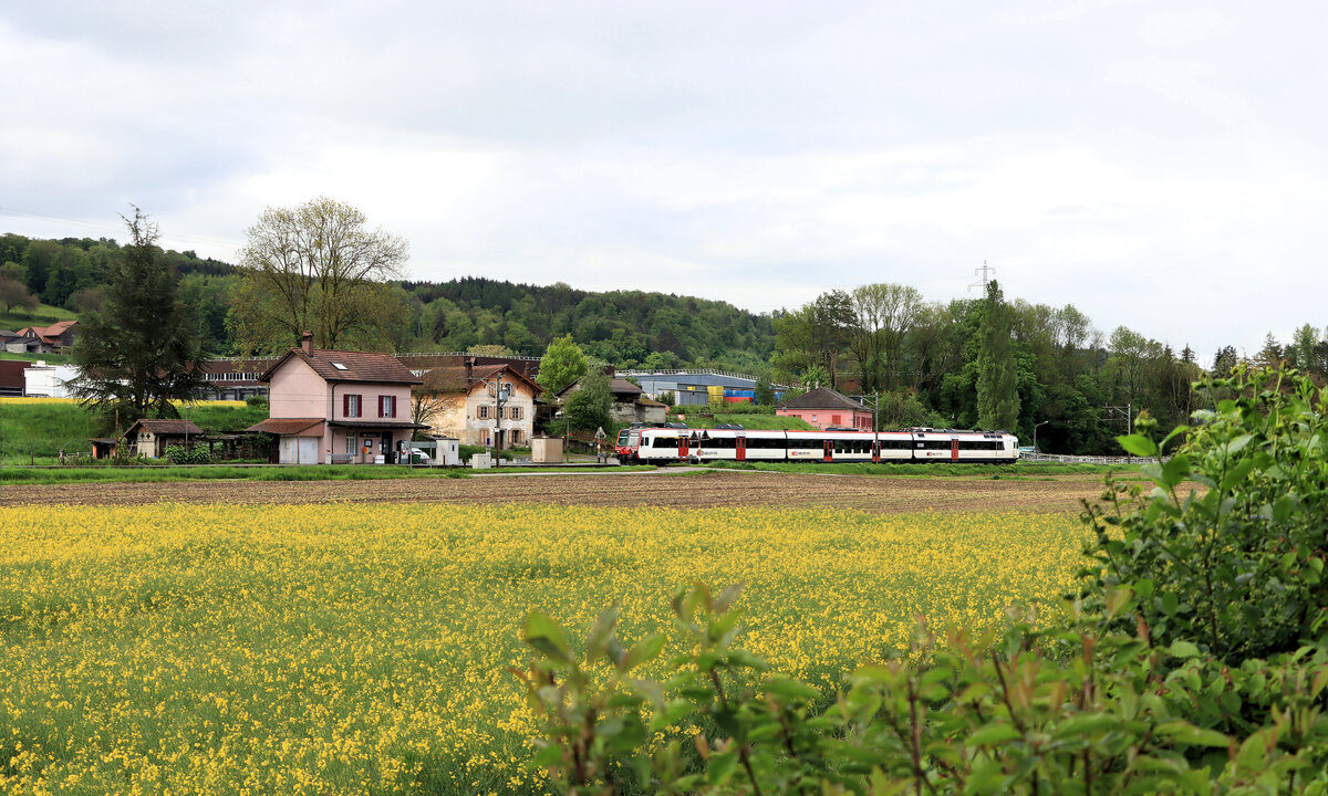 Die Broyetallinie: Durchfahrt eines Werktagszuges (gestossen von RBDe 560 269) durch die Station Henniez. Im Hintergrund die bekannte grosse Mineralwasserfabrik  Henniez . 20.Mai 2021 