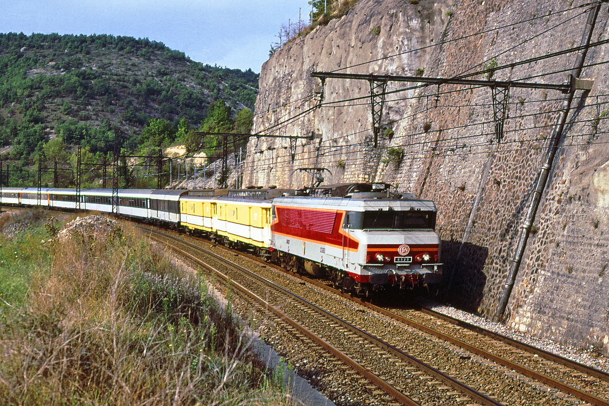 Die CC6529 der SNCF ist mit dem Rapide Paris - Limoges - Toulouse - Cerbere unterwegs im Tal des Lot, kurz vor der Stadt Cahors. Die Strecke verläuft durch einen Ausläufer des Massif Central, die Trassierung ist aufwendig, Brücken, Tunnels, Stützmauern reihen sich aneinander. Die Elektrifizierung zwischen Brive und Montauban erfolgte bereits in den Jahren 1942 bis 1943.
Cahors (Lot), Oktober 1989.
Canon A1, digitalisiert mit Canoscan.