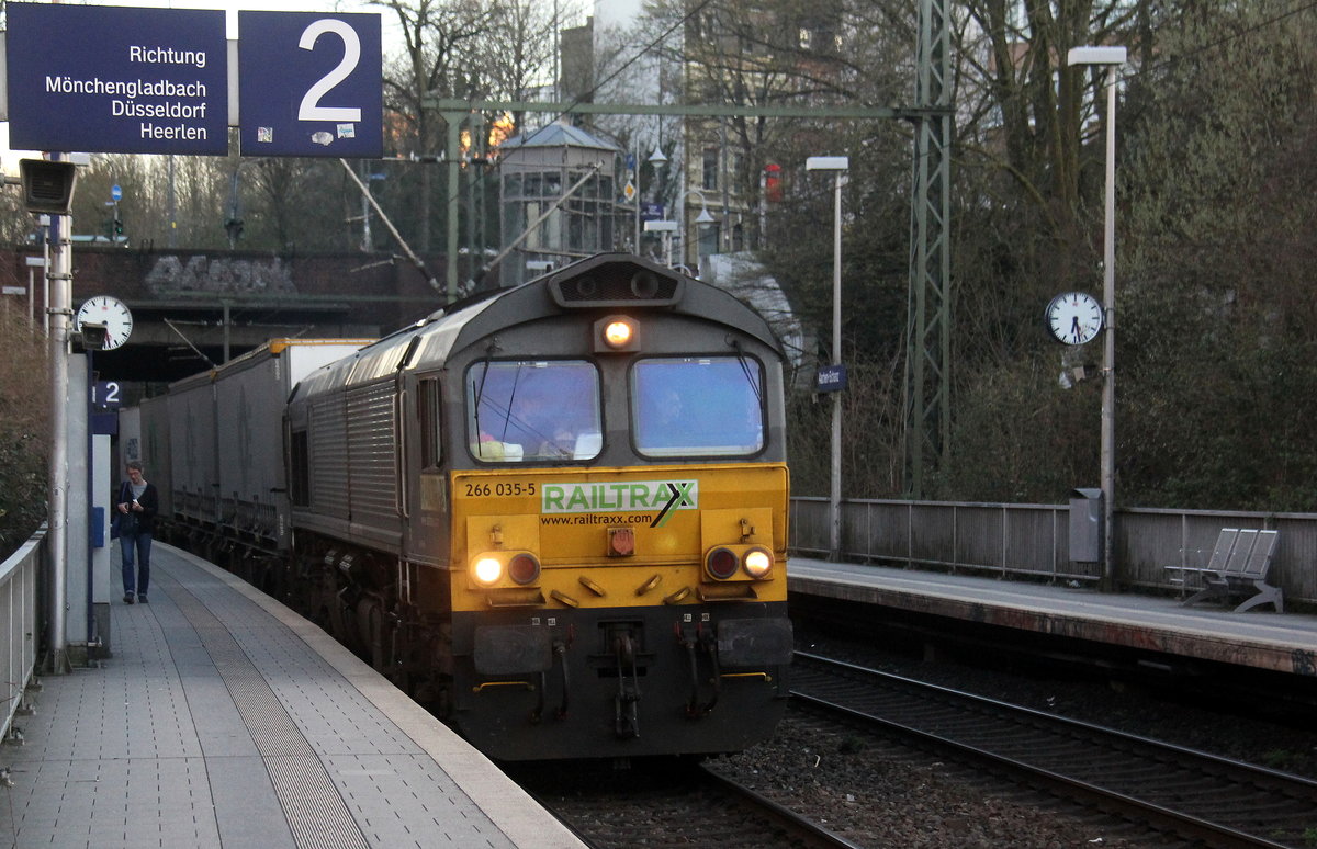 Die Class 66 266 035-5 von Railtraxx kommt mit viel Dieselpower aus Richtung Köln,Aachen-Hbf und fährt durch Aachen-Schanz mit einem Containerzug aus Köln-Eifeltor(D) nach Genk-Haven(B) und fährt in Richtung Aachen-West. 
Aufgenommen vom Bahnsteig von Aachen-Schanz. 
In der Abenddämmerung am Abend vom 22.3.2019.