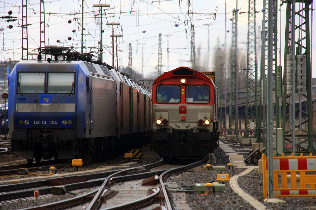 Die Class 66 DE6302 Federica von Crossrail fährt mit viel Gas mit einem langen P&O Ferrymasters Containerzug aus Gallarate(I) nach Zeebrugge(B) bei der Ausfahrt von Aachen-West und fährt in Richtung Montzen/Belgien und auf dem Nebengleis eine 145 CL-204 von Crossrail steht mit 8 E-Loks von Crossrail stehen auf dem abstellgleis in Aachen-West bei strömenden Regen und Hagel am Nachmittag vom 16.2.2014.