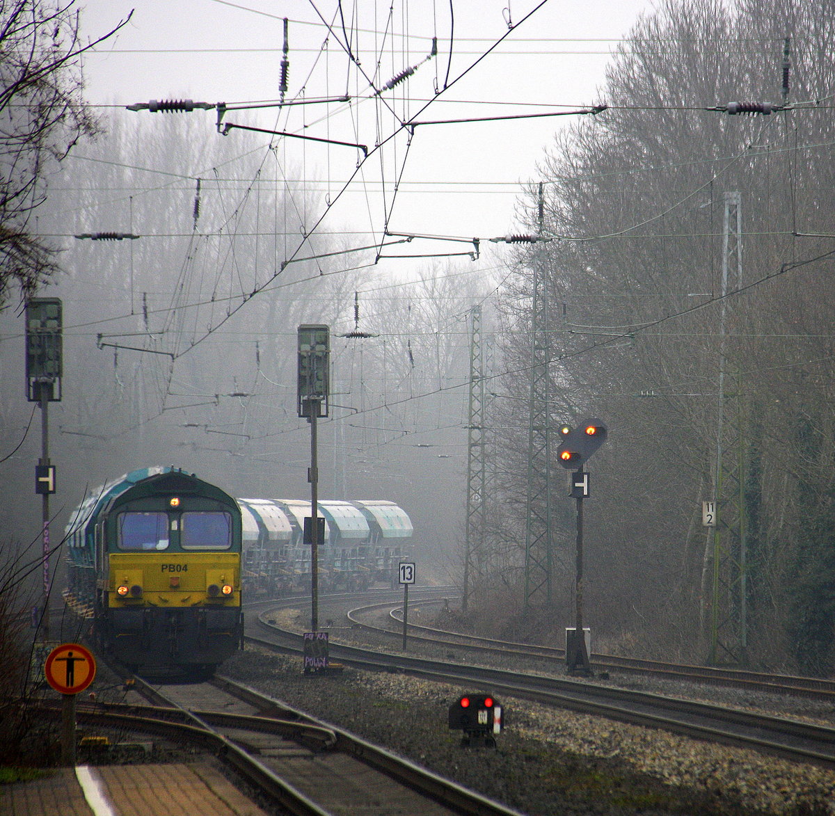 Die Class 66 PB04 von B-Logistics kommt aus Richtung Aachen-West mit einem schweren Kalkzug aus Hermalle-Huy(B) nach Oberhausen-West(D) und fährt  durch Kohlscheid in Richtung Herzogenrath,,Hofstadt,Finkenrath,Rimburg,Übach-Palenberg,Zweibrüggen,Frelenberg,Geilenkirchen,Süggerrath,Lindern,Brachelen,Hückelhoven-Baal,Baal,Erkelenz,Herrath,Beckrath,Wickrath. 
Aufgenommen von Bahnsteig 1 in Kohlscheid. 
Bei Sonne und Nebelwolken am Kalten Vormittag vom 6.2.2017.