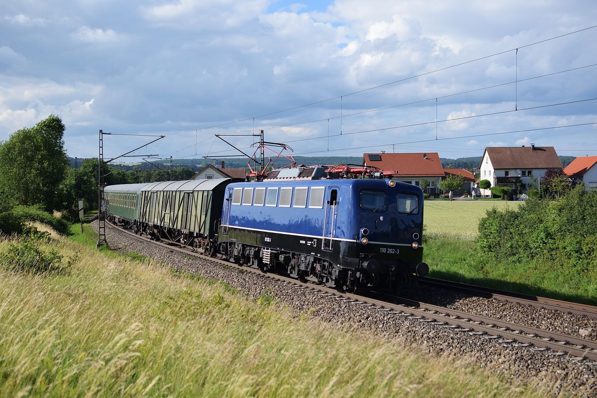 Die cobaltblaue 110 262 der BayernBahn zieht am 22.Juni 2018 einen Zug aus aus einigen Museumswagen nahe Westerstetten über die Schwäbische Alb nach Günzburg/Augsburg.