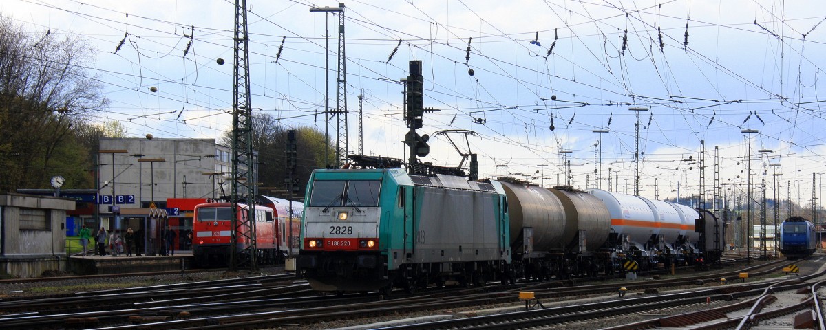 Die Cobra 2828 fährt mit einem Kurzen gemischten Güterzug aus Köln-Gremberg nach Antwerpen-Noord(B) bei der Ausfahrt aus Aachen-West und fährt in Richtung Montzen/Belgien und im Hintergrund steht eine 185 535-2 von Crossrail und Zwei 185er von Crossrail  stehen auf dem Abstellgleis in Aachen-West bei Sonne und Regenwolken am Nachmittag vom 23.3.2014.