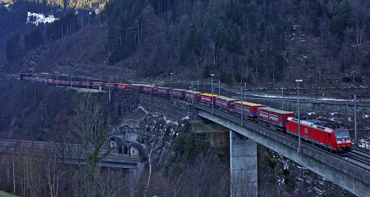 Die DB E Lok 185 121-1 schiebt an einem  Sattelaufliegerzug der Spedition Winner bei Intschi,Bild vom 6.1.2015