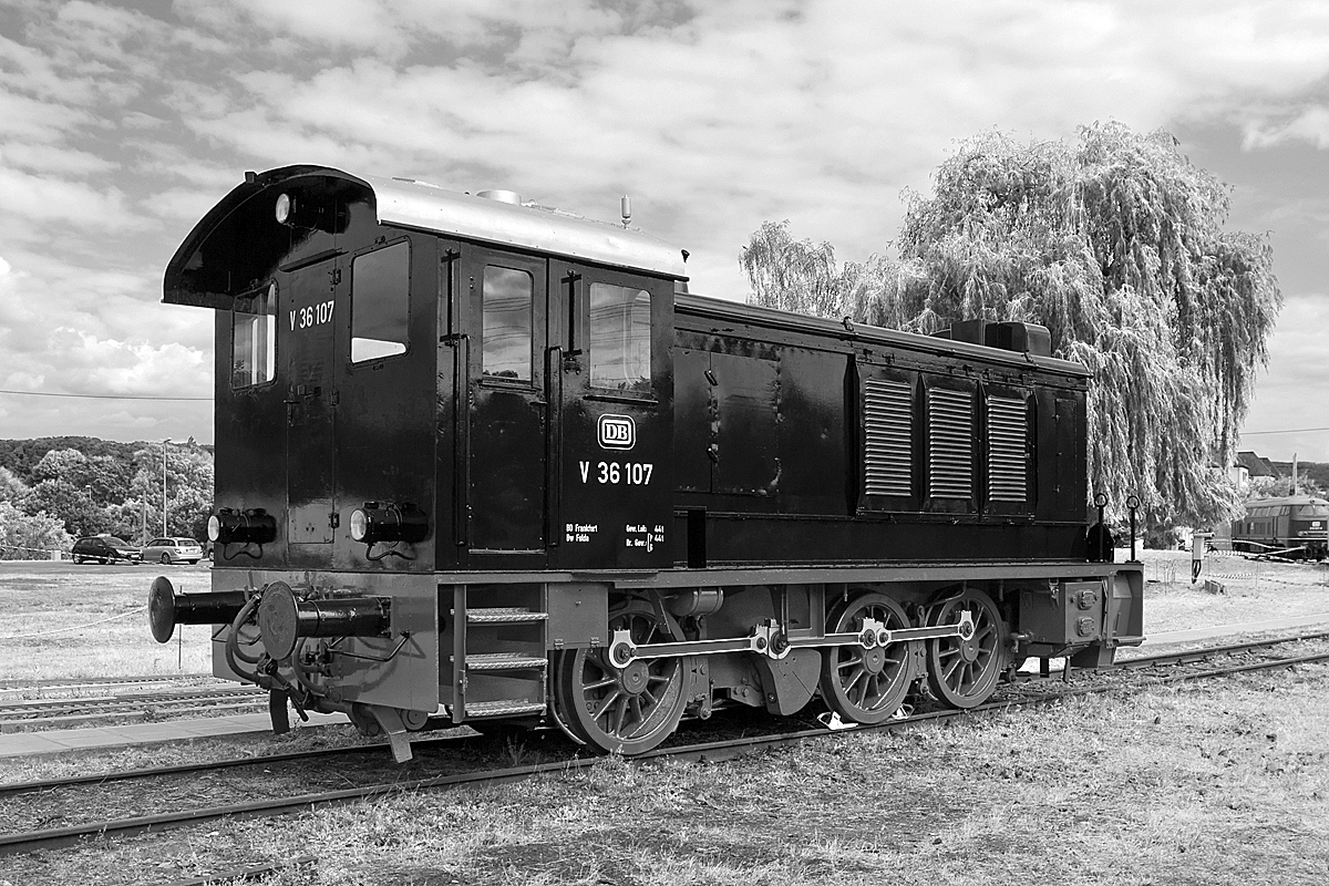 
Die DB V 36 107, ex DB 236 107-9, ex RLM 36280, am 14.06.2014 im DB Museum Koblenz-Lützel. Hier in schwarz-weiß mit Infrarotefekt.

Die Wehrmachtlokomotive vom Typ WR 360 C 14  (Wehrmachtlokomotive für Regelspur mit 360 PS, Achsfolge C und einer Achslast von ca. 14 t) wurde 1940 von der Berliner Maschinenbau AG (BMAG) unter der Fabriknummer 11216 gebaut und als Lok 36280 an RLM – Reichsluftfahrtministerium / Luftwaffe geliefert. Nach dem Krieg verblieb sie im Westen und kam so zur Deutschen Bundesbahn (DB), hier wurde sie bis 1968 als DB V 36 107 bezeichnet, mit Einführung des DB-EDV-Nummernschemas wurde sie als DB 236 107-9 bezeichnet, bis sie 1977 bei der DB ausgemustert wurde. Nach der Ausmusterung blieb sie in Bremen als zur museale Erhaltung bzw. als Denkmallok, bis sie 2013 zum DB Museum Koblenz-Lützel kam.