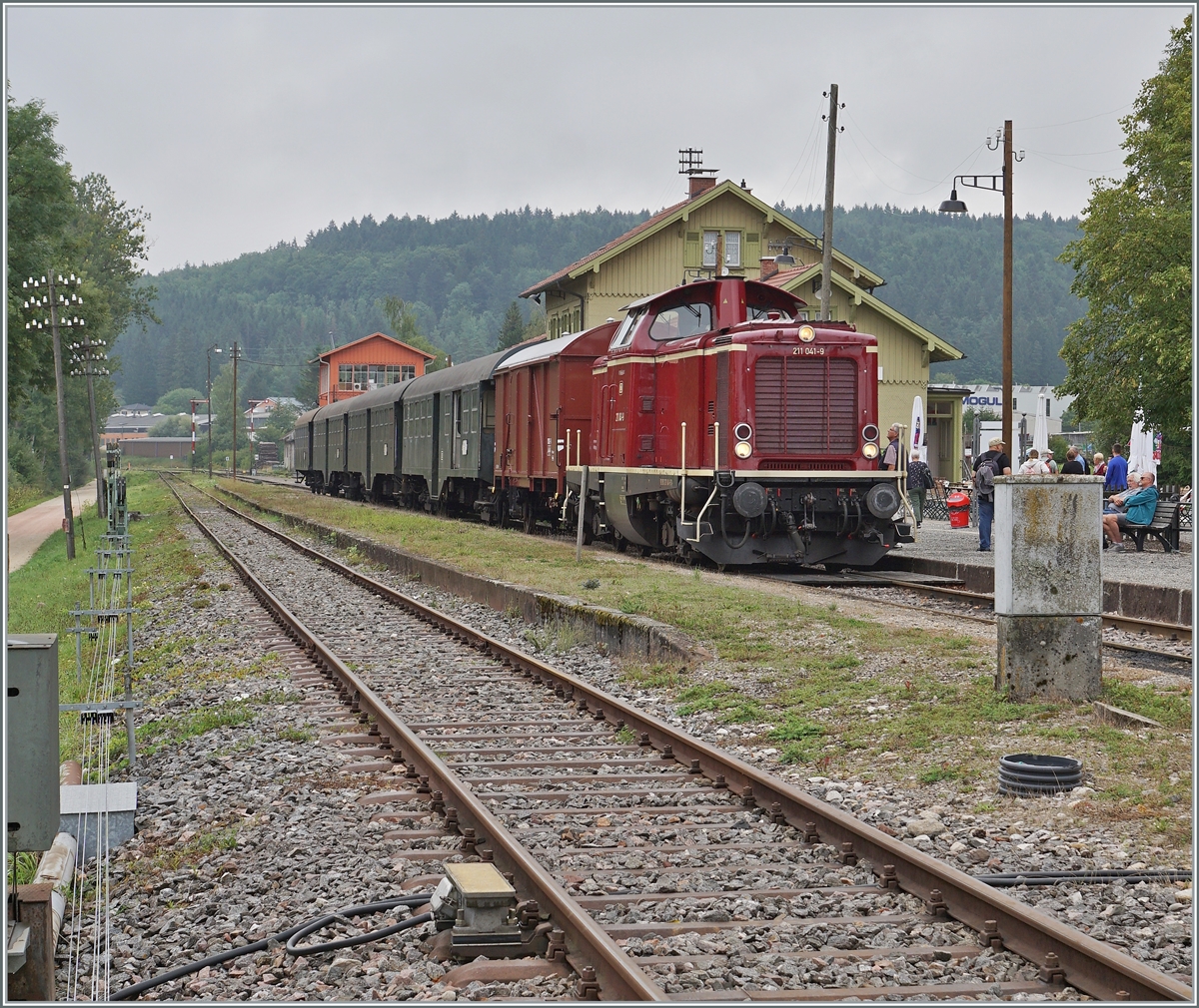 Die Diesellok 211 041-9 (92 80 1211 041-9 D-NeSA) mit einem stimmigen Zug aus Umbauwagen wartet als  Morgenzug  im Bahnhof Zollhaus Blumberg auf die Abfahrt.
Die Aufnahme entstand beim offenen Bahnübergang. 

27. August 2022