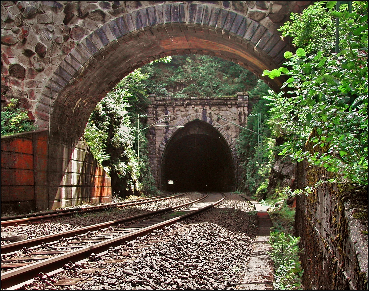 Die doppelten Tunnelportale der Schwarzwaldbahn sorgen immer wieder für Erstaunen. Das Portal des Eisenbergtunnels, Offenburger Seite, ist durch die Anlehnung an die Gothik eine besondere Schönheit. Auch zeugen die großen Felsbrocken im Gemäuer vom Originalzustand des Portals. Betrachtet man historische Aufnahmen, so scheinen die Mauern mit feineren Steinquardern neueren Datums zu sein. Niederwasser, August 2006.

Der Fotograf stand bei der Aufnahme gut überwacht deutlich neben den Gleisen. Auch bitte die Qualität entschuldigen, die Aufnahme entstand noch mit einer 3-MPx-Kamera.