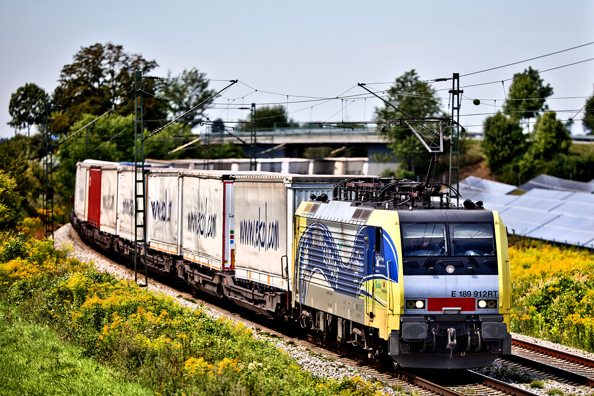 Die E 189 912 RT fährt in Langenisarhofen mit einem Ekol Sattelaufliegerzug vorüber.Bild 8.8.2017