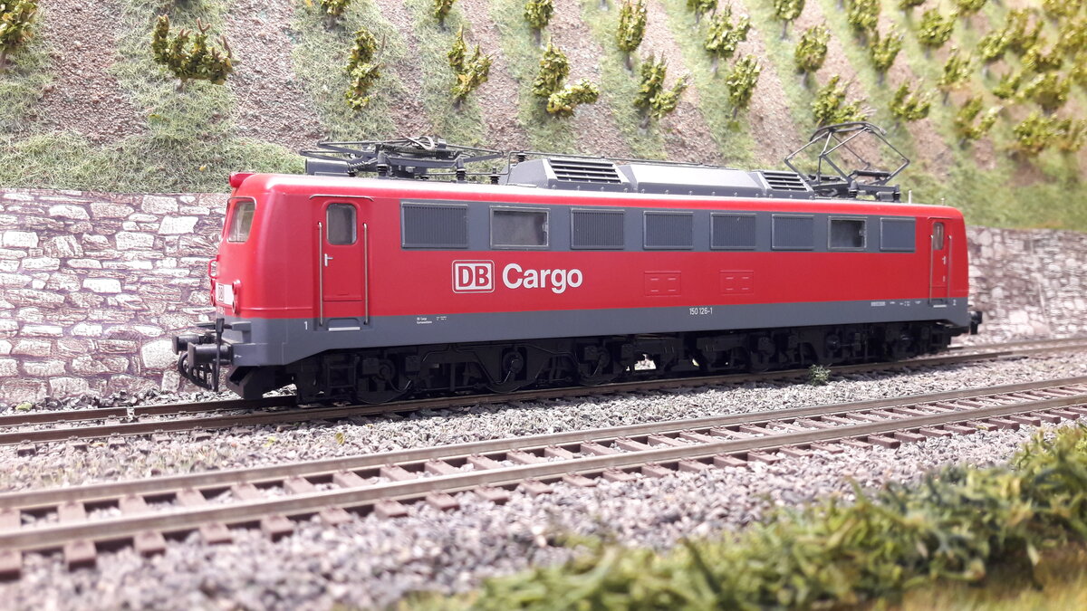 Die Einheitslok der DB, die E10. 1950 wurde die Planung in Auftrag gegeben, 1952 die erste ausgeliefert. es gab 5 Vorserienloks, E10 001-5 . 001 hatte noch ein ganz anderes Aussehen . 002-005 waren äußerlich fast Baugleich, außer 002, die hatte 3 gleiche Frontfenster. Die Serienloks bekamen letztendlich das heutige Aussehen, ebenso wie die Baureihen E40 / E41 und die E50 , welche ja auch zu den Einheitsloks zählen. Die E10 veränderte ab 288 Ihr Aussehen in die heutige Bügelfalte. Ich werde Euch mal soweit mein Bestand reicht, alle Variationen aufführen. Hier nun die Einheitslok als 6 achsige schwere Güterzuglok 150 126-1, Variante verkehrsrot DB Cargo, keine Regenrinne, Klatte Lüfter und viereckige Maschinenraumfenster, keine Griffstange vorne, Doppellampen . Modell Roco 62427 DC digital