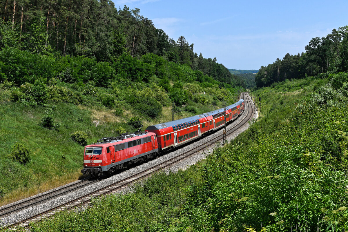 Die vom Einsatz gezeichnete 111 159 konnte ich am 19. Juni 2022 vor dem RE 4856 nach Nürnberg HBF im Einschnitt bei Sinngrün in der Oberpfalz fotografieren. 