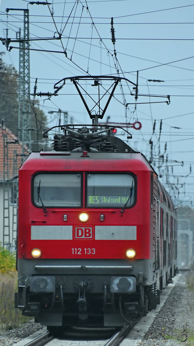 Die Elektrolokomotive 112 133 zieht RE5 nach Stralsund Hbf, hier im November 2020 kurz vor der Ankunft am Bahnhof Demmin.