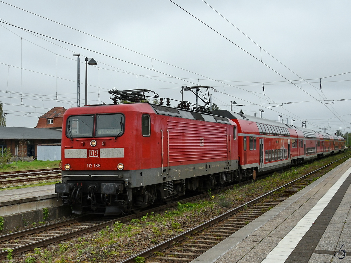 Die Elektrolokomotive 112 186 zieht eine RE-Doppelstockgarnitur in Richtung Rostock. (Neustrelitz, Mai 2021)