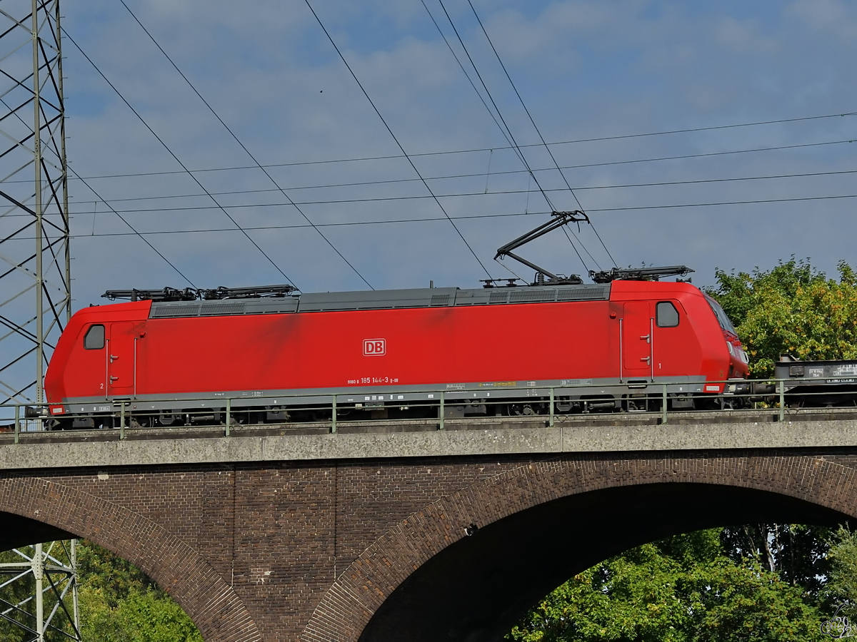 Die Elektrolokomotive 185 144-3 befährt die Hochfelder Eisenbahnbrücke, so gesehen Ende August 2022 in Duisburg.