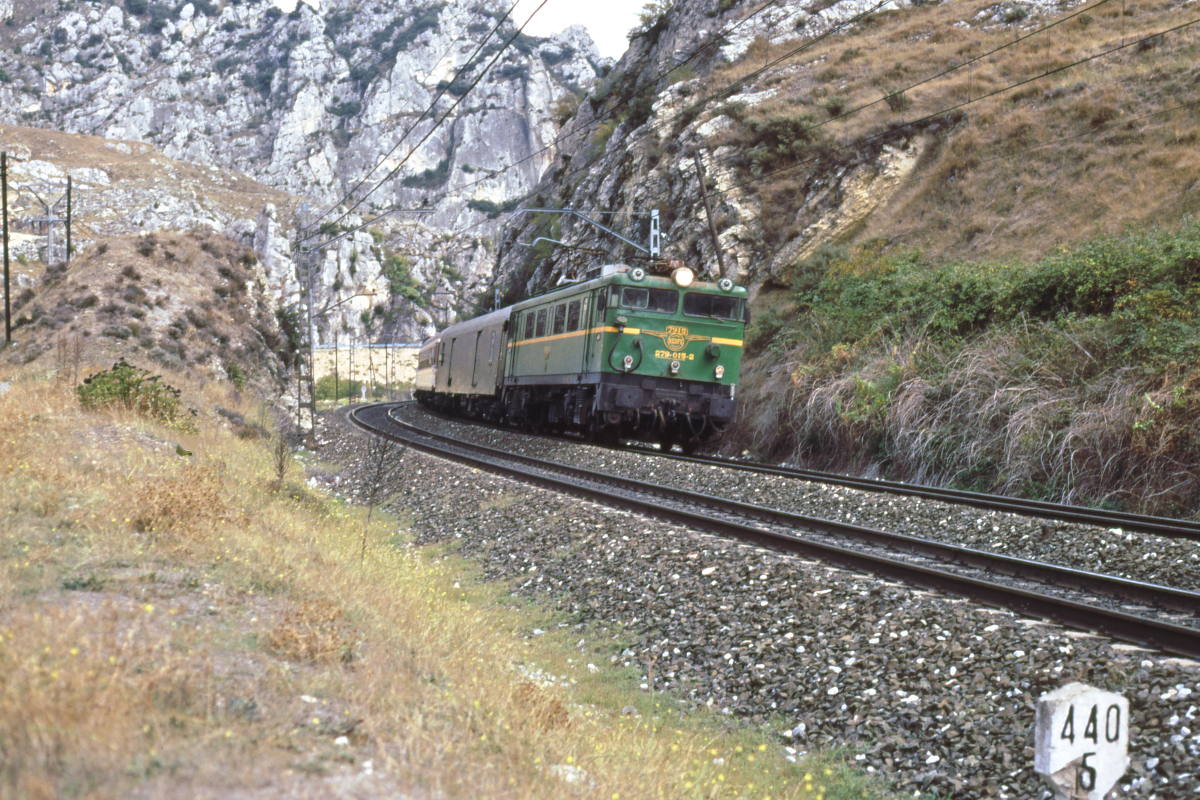 Die ersten japanischen Lokomotiven auf spanischen Gleisen bildete die Baureihe 279. Die 16 Lok wurden ab 1967 in Dienst gestellt, ihre Dienstmasse betrug 80 t, die Nennleistung 2700 kW. Die ersten beiden Maschinen wurden bei Mitsubishi gefertigt, der Rest bei CAF in Lizenz. Hier durchfährt die 279 015 die Schlucht von Pancorbo mit dem Rapido Irun/Bilbao - Salamanca, welchen sie bis Medina del Campo führen wird. Bis Mitte der 1980er Jahre fuhr der Zug weiter nach Caceres, mit Stillegung der Strecke ab Salamanca endete der Zug bereits dort.
Pancorbo (Burgos), 11. Oktober 1989
