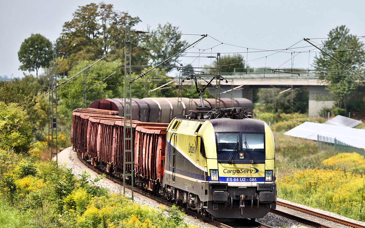 Die ES 64 U2-081 Cargo Serv fährt am 3.8.2017 in Langenisarhofen mit einem Stahlzug vorüber.