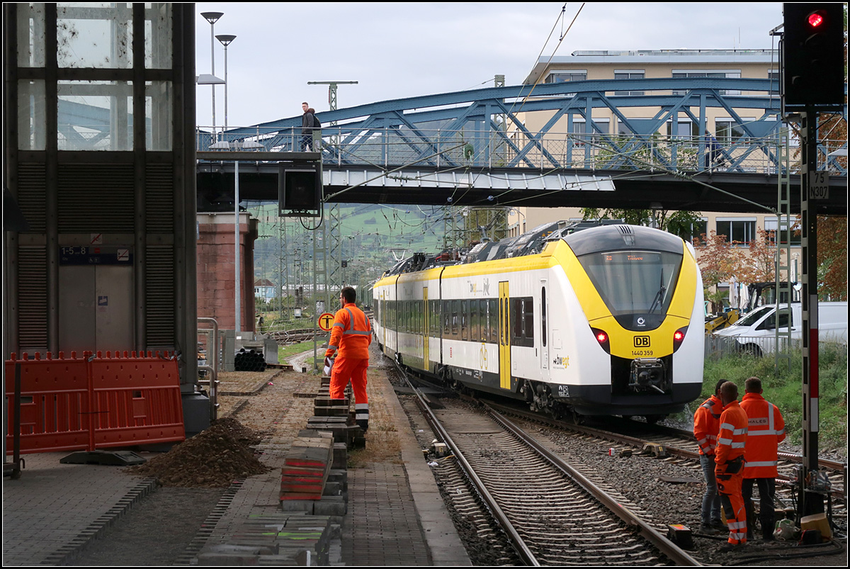 Die Farben stehen im gut -

Ein weiß-gelb-schwarzer Triebzug der Baureihe 440 zwischen orangen Männern bei der Abfahrt im Hauptbahnhof von Freiburg,

07.10.2019 (M)