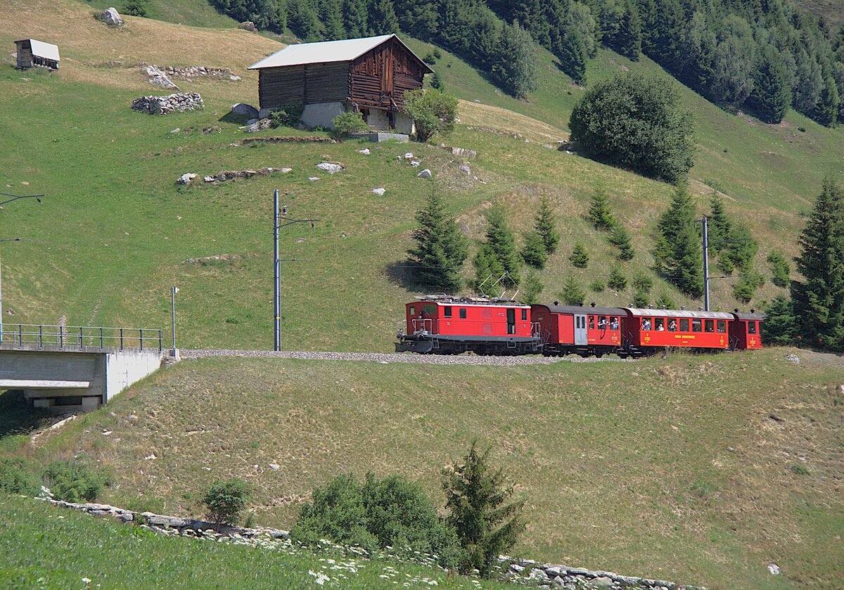 Die FO 36, �ber 80 Jahre alt, zieht am 05.07.2026 den Jubil�umszug, im Rahmen der Feierlichkeiten zu 100 Jahre Furka-Oberalp-Bahn, von Diesentis her zum Oberalppass. Aufgenommen habe ich das Bild kurz nach Rueras in der Surselva.
Die im Zug verwendeten Wagen geh�ren der DFB.