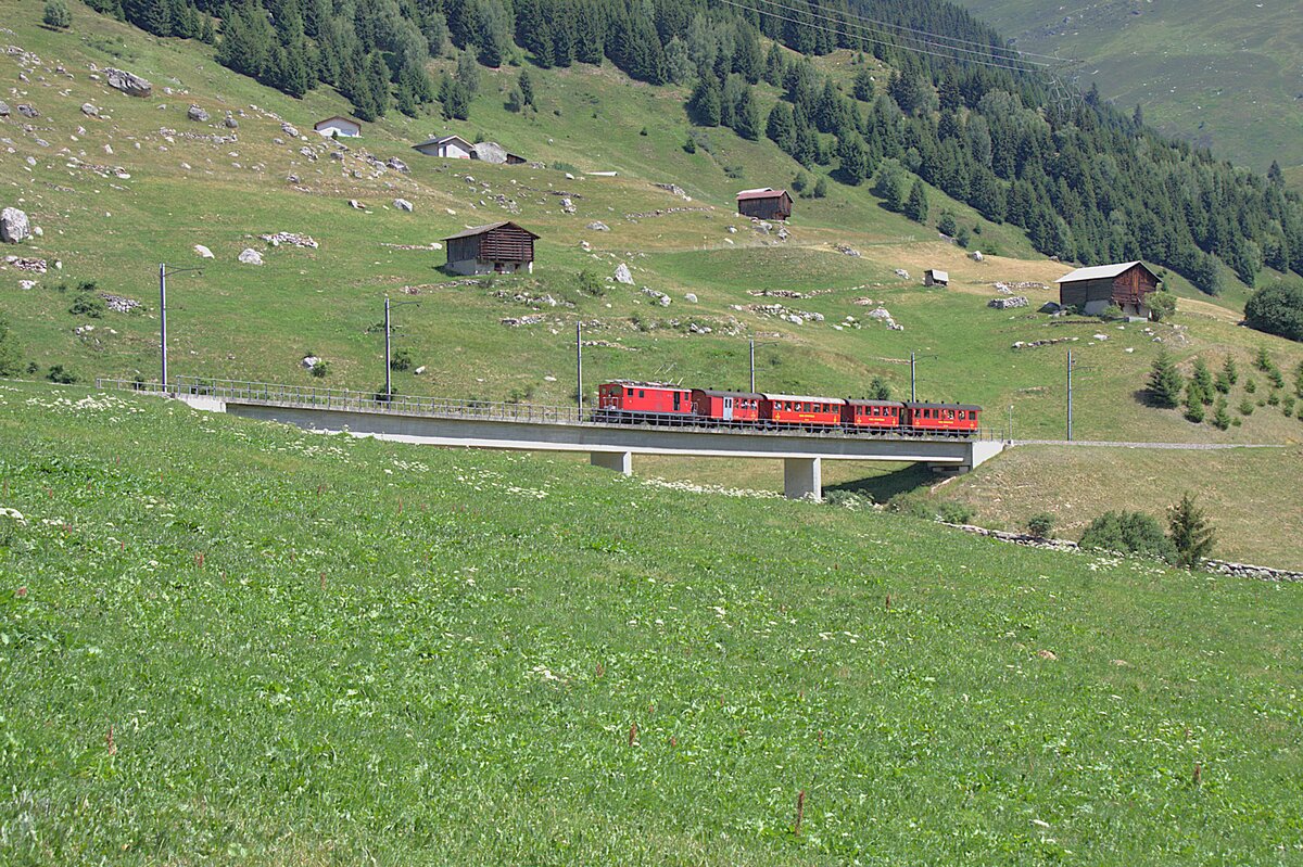 Die FO 36, �ber 80 Jahre alt, zieht am 05.07.2026 den Jubil�umszug, im Rahmen der Feierlichkeiten zu 100 Jahre Furka-Oberalp-Bahn, von Diesentis her zum Oberalppass. Aufgenommen habe ich das Bild kurz nach Rueras in der Surselva.
Die im Zug verwendeten Wagen geh�ren der DFB.
Bevor die ersten Triebwagen abgeliefert wurden, waren da solche Kompositionen auch als Personenz�ge unterwegs