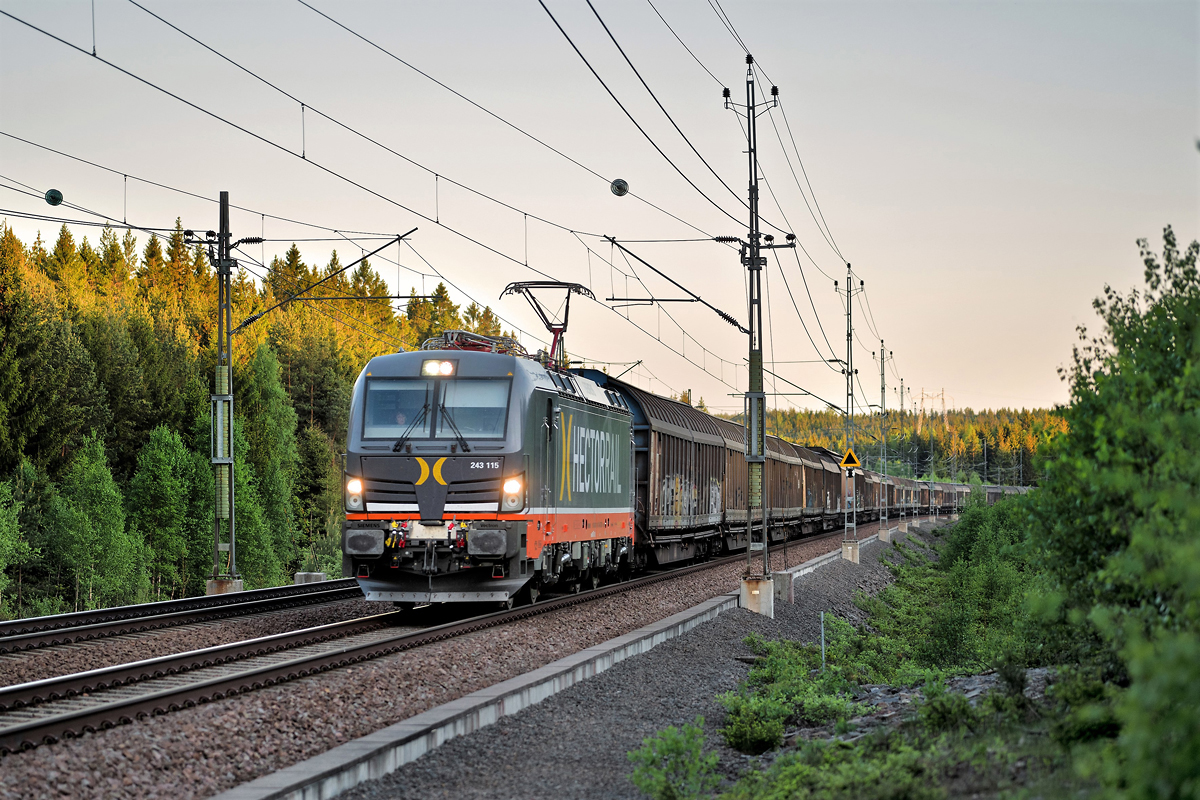 Die frisch nach Schweden überführte Hectorrail 243 115 fährt beim Einnachten bei Degerön mit einem langen Schiebewandwagenzug vorüber.Bild 19.5.2018