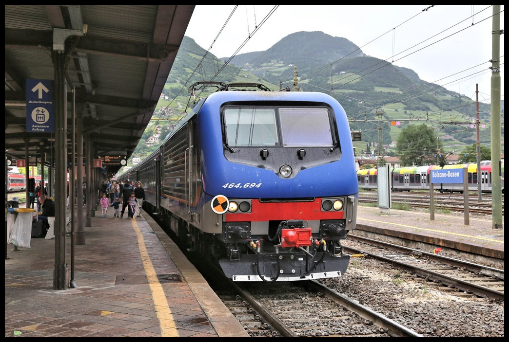 Die FS Lokomotive 464.694 wartet hier am 29.5.2022 um 14.26 Uhr am Bahnsteig im Hauptbahnhof Bozen mit ihrem Regionalexpress auf die Weiterfahrt nach Bologna.