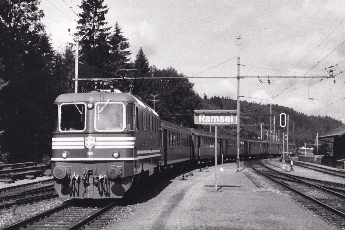 Die für das
100 JAHRE GOTTHARD JUBILÄUM
dekorierte grüne Re 4/4 II 11160 noch mit runden Lampen in Ramsei am 4. Juli 1981.
An diesem Tag brachte sie den Fahnenextrazug ab Luzern über Huttwil nach Burgdorf, wo das Eidgenössische Jodlerfest stattfand. In Ramsei wurde für die Weiterfahrt die Lok umgesetzt.
Hier handelt es sich um eine meiner ältesten Aufnahmen des Loktyps BOBO Re 4/4.
Foto: Walter Ruetsch 
 
