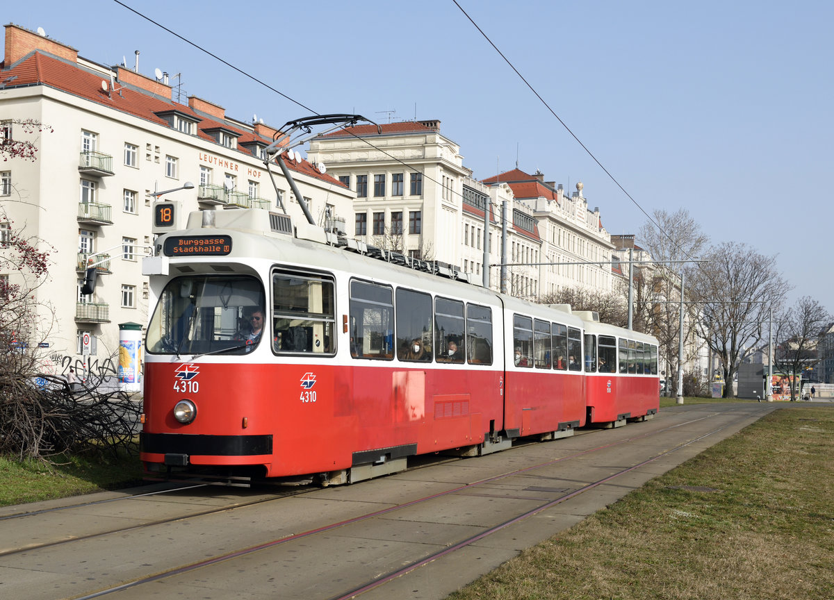 Die Garnitur bestehend aus E2 4310 und Beiwagen c5 1510 war am 23.02.2021 auf der Linie 18 unterwegs und wurde von mir unweit der Station Margaretengürtel fotografiert, im Hintergrund zu sehen ist die  Mollardburg , erste Zentralberufsschule Wiens, erbaut zwischen 1909 und 1911 zu sehen. 

