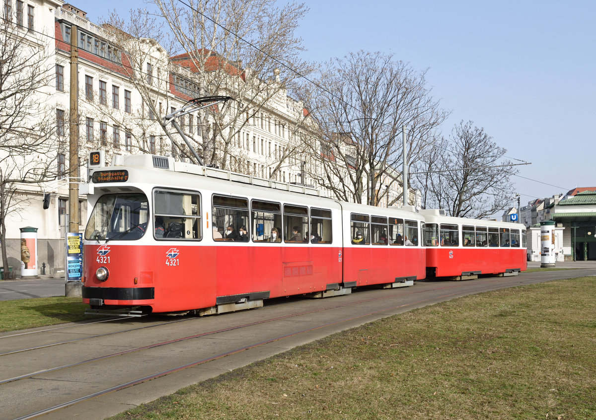 Die Garnitur bestehend aus E2 4321 und Beiwagen c5 1477 war am 23.02.2021 auf der Linie 18 unterwegs und wurde von mir unweit der Station Margaretengürtel fotografiert, im Hintergrund zu sehen ist die  Mollardburg , erste Zentralberufsschule Wiens, erbaut zwischen 1909 und 1911 zu sehen. 