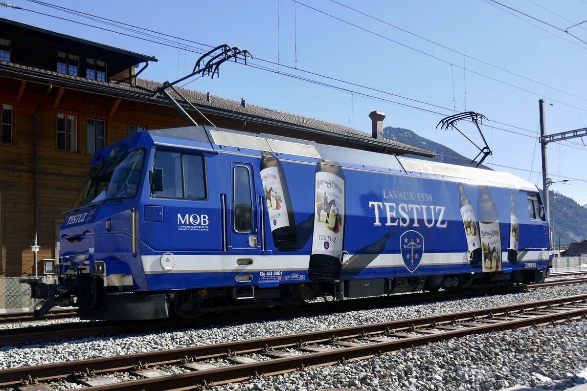 Die Ge 4/4 8001 der MOB mit Werbung für Testuz Wein am 19.2.23 hinter dem Bahnhof Zweisimmen abgestellt.