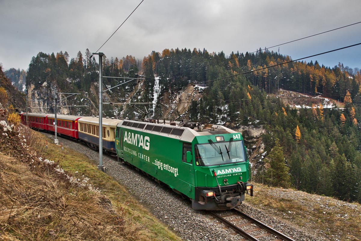 Die Ge 4/4 III 647 fährt in Filisur mit einem Re von St.Moritz nach Chur am Hochnebeltag des 14.11.2016 talwärts.