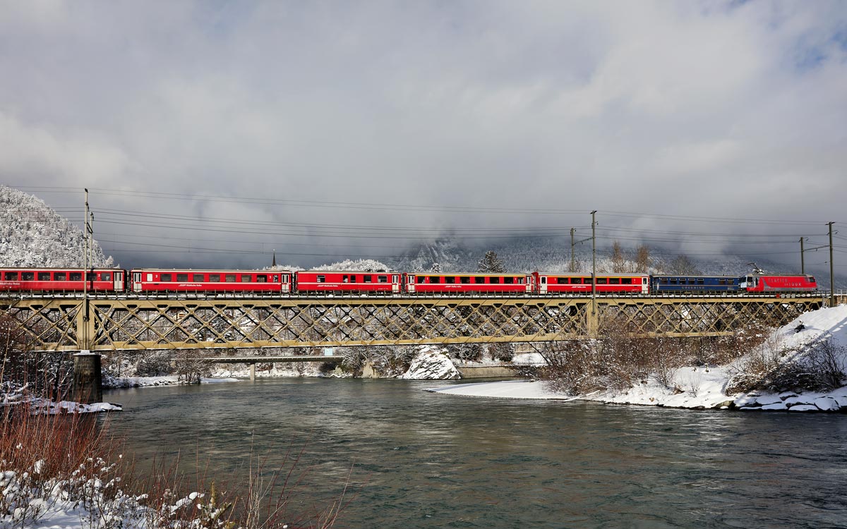 Die Ge 4/4 III 651  Glacier on Tour  fährt mit einem Re über die Rheinbrücke in Reichenau-Tamins.Bild 16.1.2017