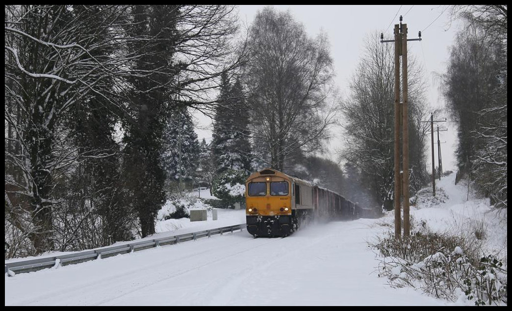 Die goldfarbene Beacon Class 66 Nr. 653-07 ist seit ein paar Monaten die Standardlok für den Schrott Zug Verkehr zwischen Osnabrück Hafen und dem Stahlwerk in Georgsmarienhütte. Am 9.2.2021 war der erste Tag, wo sie auch bei winterlicher Bedingung auf der Hüttenbahn unterwegs war. Hier kehrt sie gerade um 10.12 Uhr mit dem Leerzug aus Georgsmarienhütte zurück. Deutlich erkennt man den Brechpunkt der Bahnstrecke, der genau an der Ortsgrenze Hasbergen zu Holzhausen liegt. Während die Wagen noch in der Geraden am ehemaligen Bahnhof Patkenhof unterwegs sind, neigt sich die Lok bereits in die nun bis Hasbergen abfallende Strecke.d x