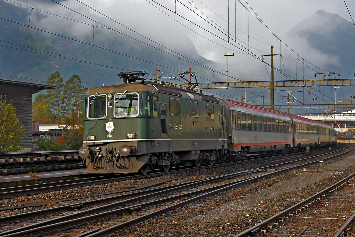 Die grüne Re 4/4 II 11161 braust bei Weesen mit dem Ec von Zürich HB nach Graz Hbf am verlassenen Bahnhof Weesen vorüber.Bild vom 16.10.2014