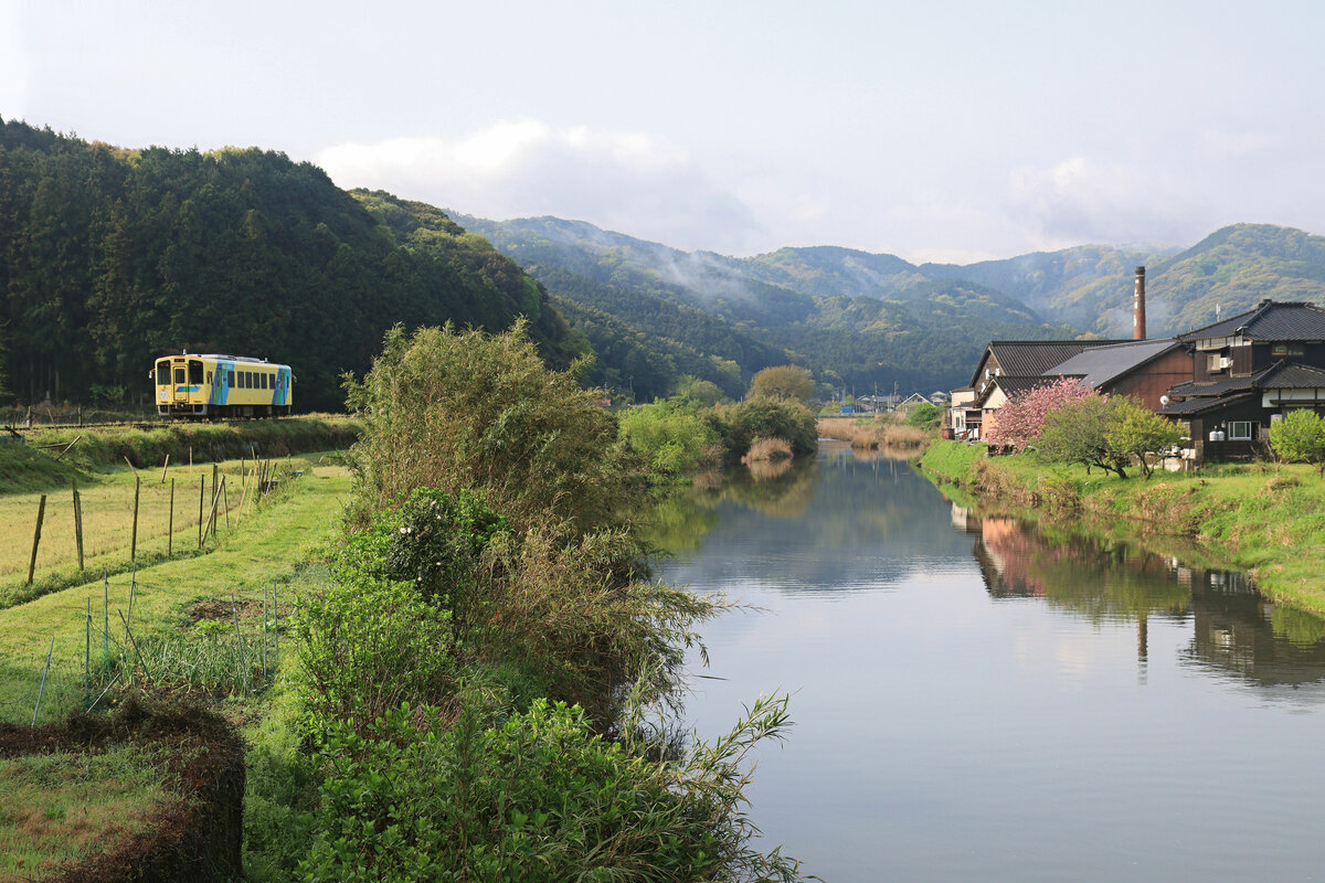 Die Heisei Chikuhô Bahn im Nordosten der Insel Kyûshû: Triebwagen 404 zieht leise durch die Landschaft von Sakiyama, rechts im Bild ein ganz altes Sake (Reiswein)-Brauhaus. 16.April 2023 
