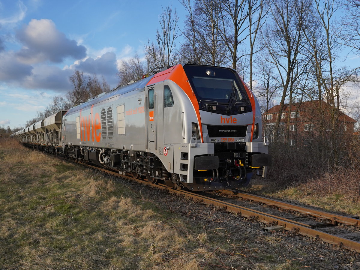 Die HVLE-159 006(90 80 2159 006-6 D-HVLE), eine 2020 von Stadler in Valencia gebaute Lok des Typs Eurodual-D, ist mit einem langen Zug aus Schüttgutwagen des Typs Faccns von GATX unterwegs für den Umbau des Bahnhofs Sande.

2021-03-19 Sande