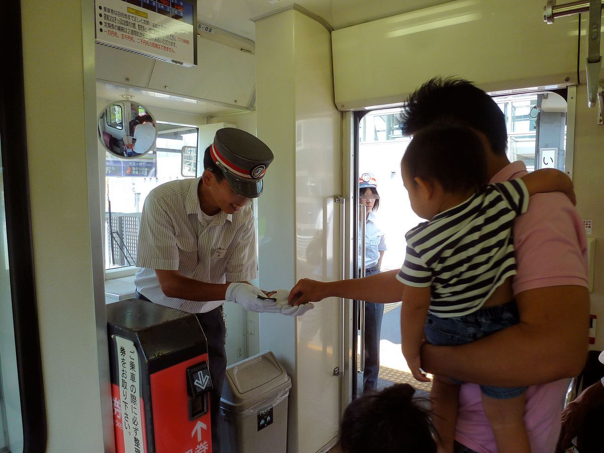 Die Ibara-Bahn legt grössten Wert auf eine enge Bindung an die lokale Bevölkerung. Auf sehr freundliche Weise nimmt der Wagenführer von Triebwagen 355-08 das Geld des Gastes für die Fahrt entgegen (Selbstkontrolle kennt Japan nicht; wenn - wie in den Agglomerationen - keine Bahnsteigsperre die Fahrkarte kontrolliert, muss dies das Personal tun, das sich auch sonst um die Fahrgäste kümmert; zum Beispiel bekam ich beim Aussteigen ein Paket Werbematerial für die kulturellen und natürlichen Sehenswürdigen der Region). 13.August 2013. 